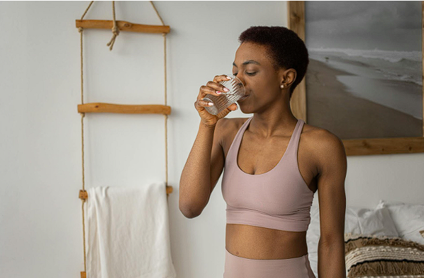 Woman in activewear drinking water.